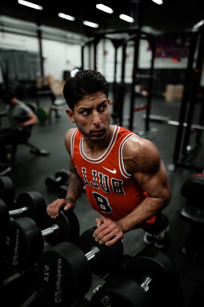 Man in a Chicago bulls red shirt practice using dumbbells to do push-ups
